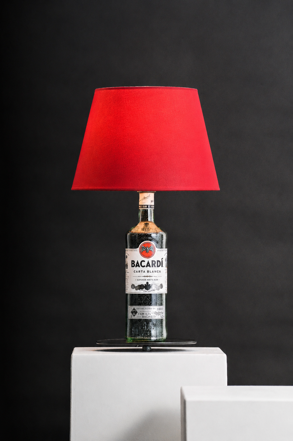 Ricardo Bacardi-Flaschenlampe mit rotem Lampenschirm vor dunklem Hintergrund
